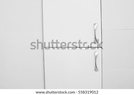 White cupboard with metallic handles in the bathroom