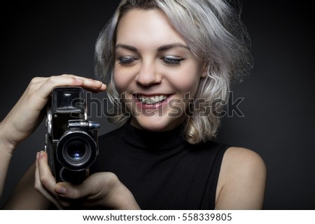 Female actor posing with a vintage camera as an artistic director, creative cinematographer or filmmaker.  She is advertising the Hollywood movie industry or film art schools.  