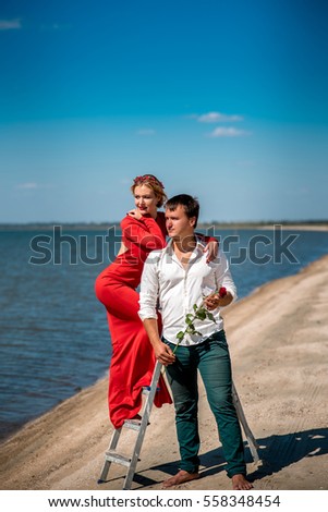 Girl standing next to the guy on the stairs by the sea.
