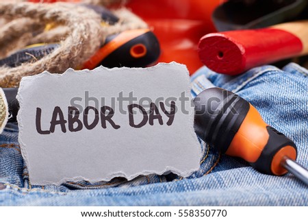 Labor Day card near screwdriver. Rope and screwdriver on jeans. Employment as part of society.