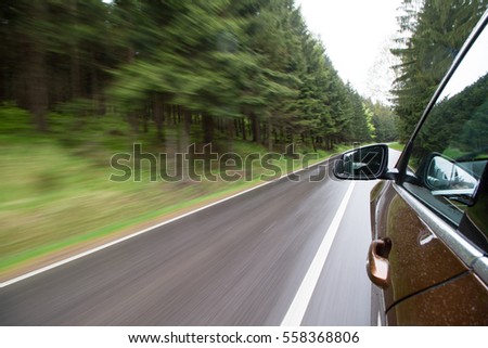 View from a bronze color car going through rainy forest