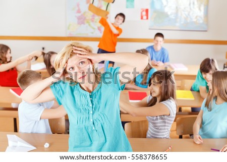 Uncontrollable pupils in classroom acting out, frustrated teacher "tearing her hair out" Royalty-Free Stock Photo #558378655