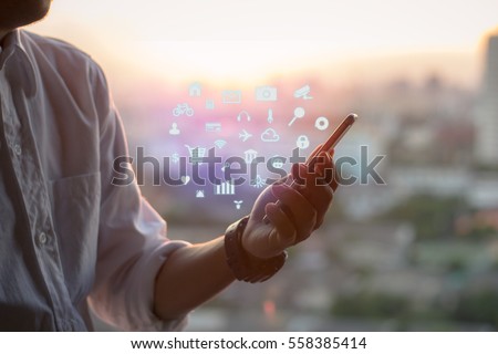 Mobile application concept.Man using touch screen smart phone on blurred urban city background,sunset Royalty-Free Stock Photo #558385414