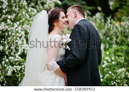 Elegant wedding couple in love background bush with white flower.