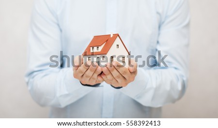 Small toy house in hands  Royalty-Free Stock Photo #558392413