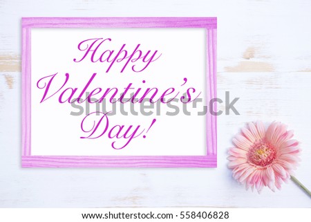 pink flower on white wooden table with frame and words Happy Valentines Day
