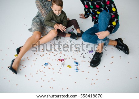 Young family of mother father and son celebrating with confetti over white background