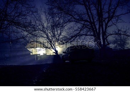 silhouette of car and trees at night forest with fog, surreal lights mystical landscape