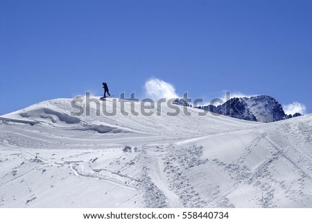 Snowboarder in terrain park at ski resort on sun winter day. Caucasus Mountains, region Dombay.