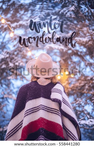 Inspirational greeting card with text "Winter wonderland" and girl wearing in hat and cozy scarf, Mood Postcard with winter park, Winter mood, Calligraphy lettering, Winter sunny background.