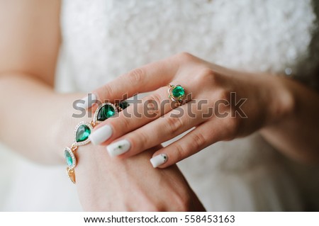 Stylish jewelry with gems of green. On the hands of women beautiful jewelry Royalty-Free Stock Photo #558453163