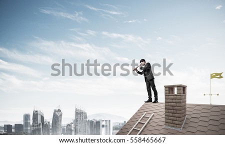 Young determined businessman standing on house roof and looking in spyglass. Mixed media