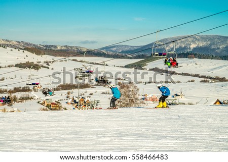 Mountain ski slope with young skiers - ski lift in the valley Royalty-Free Stock Photo #558466483