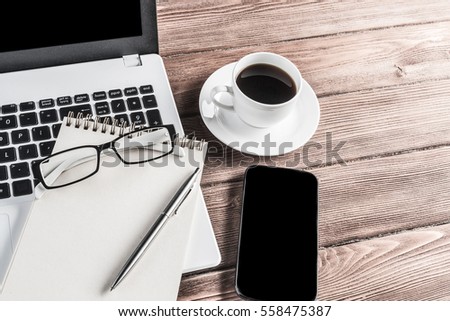 Still life photo of laptop notepad coffee glasses and other stuff on wooden table
