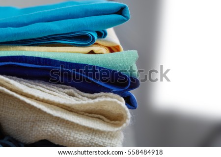 Home interior, tailor, sewing, diy concept. Heap of colorful cloth fabrics. Color Wool, cotton linen clothes. Closeup.  Royalty-Free Stock Photo #558484918