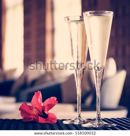 Two glasses of champagne with red flower in a spa lounge. Spa time concept. Spa lounge area. Valentines background. Romance concept. Square, tone filter  applied