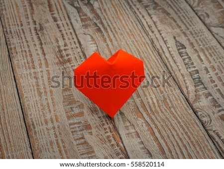 Red paper origami heart on wood background