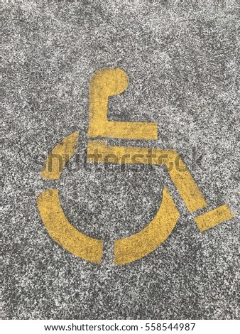 Disability parking sign stencilled in yellow onto parking space.