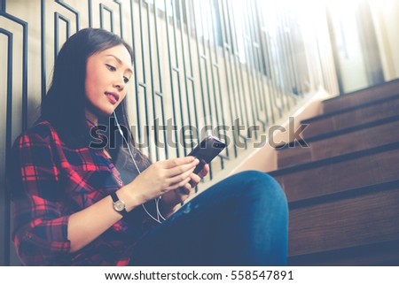 Charming beautiful woman is listening music by her smartphone and feeling chill at coffee shop cafe.