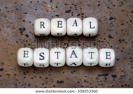 Real estate text on wooden cubes on a brown cork background