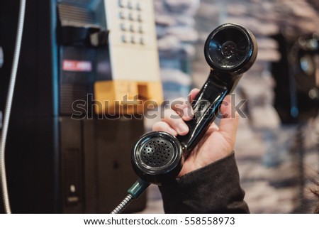 Woman's hand holding payphone Royalty-Free Stock Photo #558558973