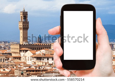 travel concept - tourist photographs Florence town with Palazzo Vecchio on smartphone with cut out screen with blank place for advertising in Italy