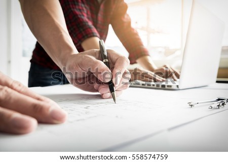 Close-up Of Person's engineer Hand Drawing Plan On Blue Print with architect equipment. Royalty-Free Stock Photo #558574759