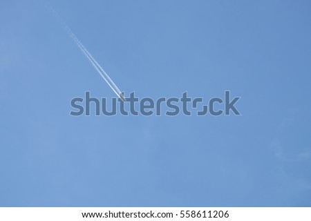 Flying airplane on the blue sky with white trace line behind