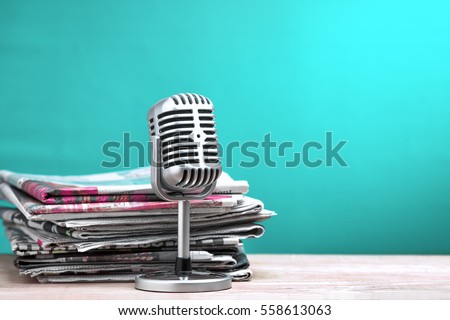 Retro microphone with newspaper on wooden table - announcement concept Royalty-Free Stock Photo #558613063