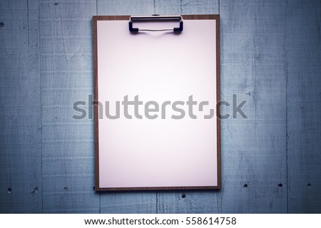 Clipboard with white sheet on wood background. Top view.Vintage style. Mock up for word.