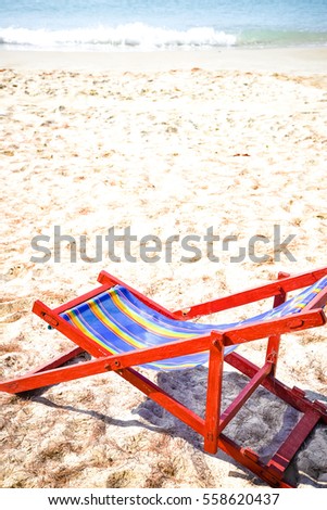 Deckchair, chair on the beach in sunshine day. Empty colorful wooden beach chair on tropical beach with blue sky background in vintage retro tone. To represent the meaning of summer vacation time.