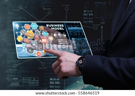 Business, Technology, Internet and network concept. Young businessman working on a tablet of the future, he sees the inscription: business model  Royalty-Free Stock Photo #558646519