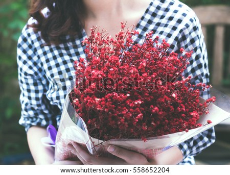 Young woman is holding red bouquet.