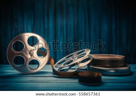 35 mm film reels and cans with dramatic lighting on a wooden background