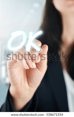Businesswoman hand writing ok on virtual screen.