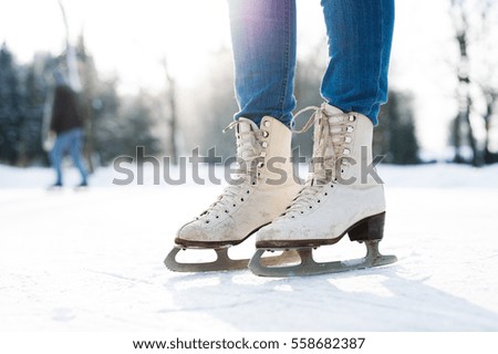 Legs of unrecognizable woman ice skating outdoors, close up.