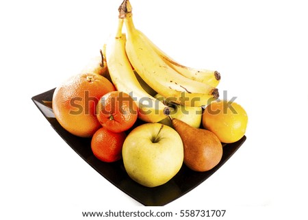 Fruit mix. Fresh fruits isolated on a white background. Studio photo. Apple banana mandarin lemon pear orange grapefruit winter fruits. Fruit concept with black plate.