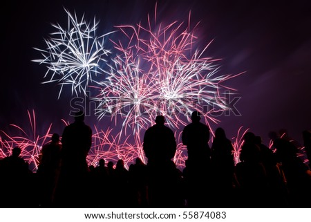 Big fireworks with silhouetted people in the foreground watching
