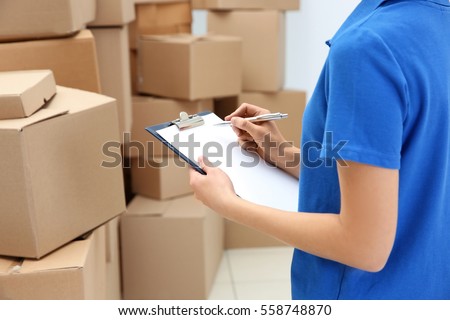 Young woman with clipboard at warehouse, closeup Royalty-Free Stock Photo #558748870