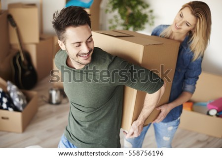 Couple carrying heavy moving boxes together  Royalty-Free Stock Photo #558756196