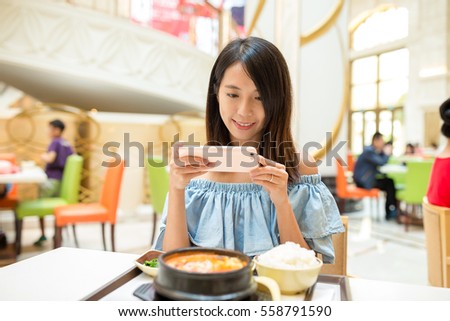 Woman taking photo on cellphone in restaurant