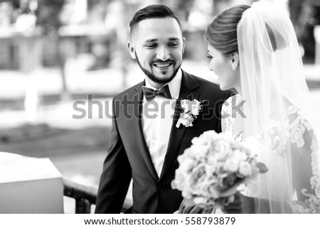 Black and white picture of handsome bearded groom admiring pretty bride