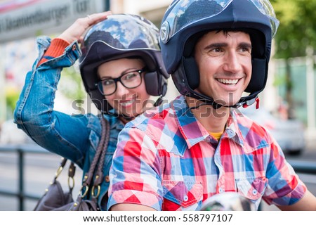 Smiling girl with glasses sitting on pillion seat of scooter Royalty-Free Stock Photo #558797107