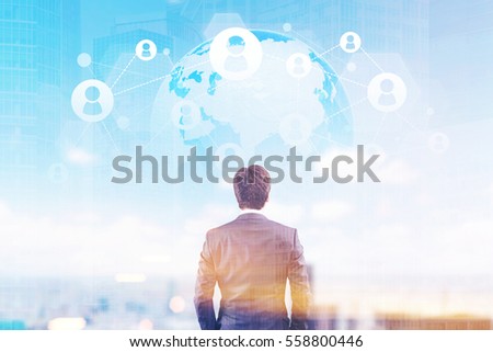 Rear view of a businessman in a suit looking at a network sketch against a globe in a sky. Cityscape is in the background. Double exposure. Toned image. Elements of this image furnished by NASA