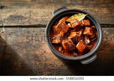 Whole pot of goulash in an aerial view with copy space on brown wooden table Royalty-Free Stock Photo #558816505