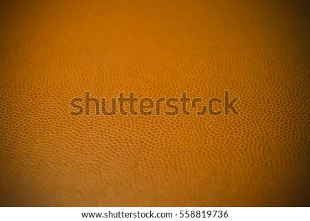 Vignetted artificial dark orange leather texture close up