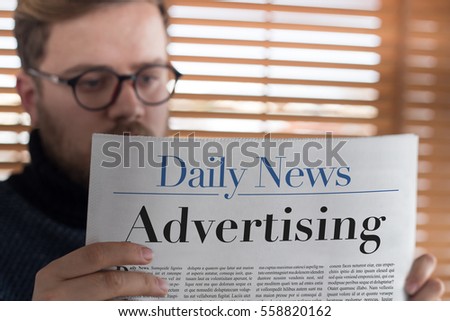 Man reading Advertising headlined newspaper