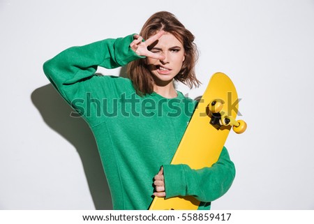 Photo of gorgeous skater lady dressed in green sweater standing isolated over white background with skateboard.