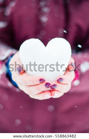 in the hands of a girl holding a heart of ice, winter object, a symbol of love