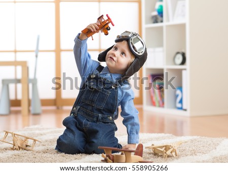 happy child toddler boy playing with toy airplane and dreaming of becoming a pilot Royalty-Free Stock Photo #558905266